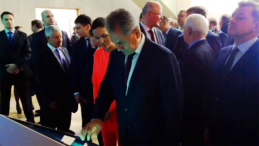 Sergey Shoygu, the President of the Russian Geographical Society and Minister of Defense of the Russian Federation, is studying the interactive installation.